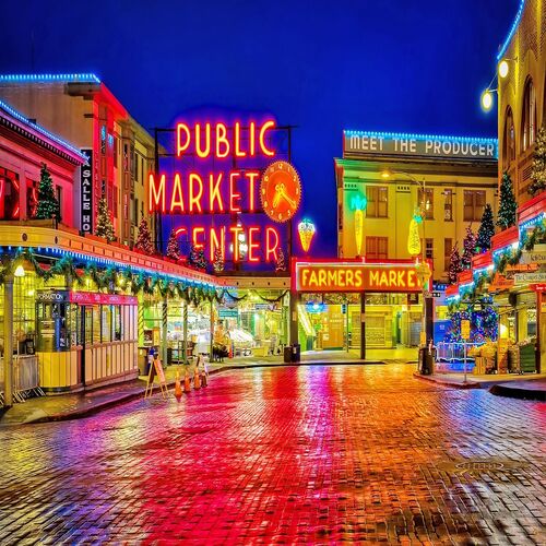Night view of Pike Place Market with glowing neon signs and reflections